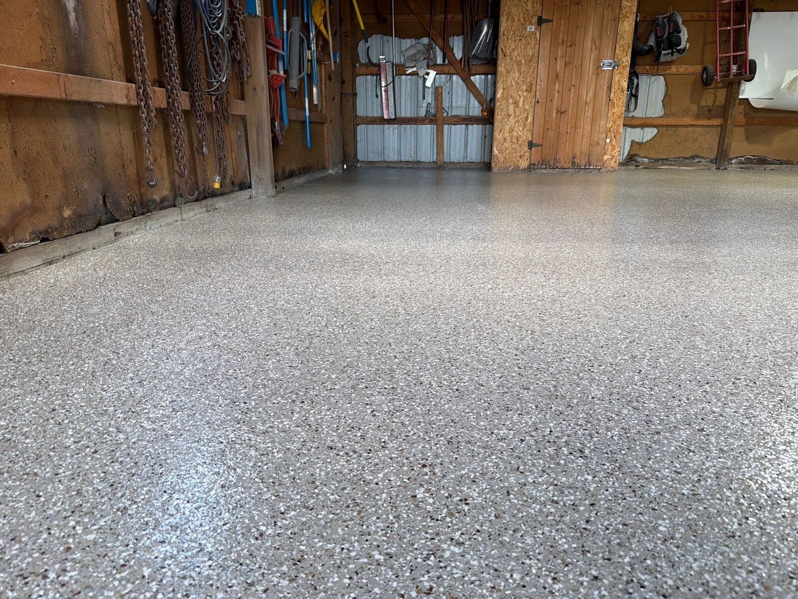 Finished gray decorative flake floor with a glossy top coat in a wood-walled garage