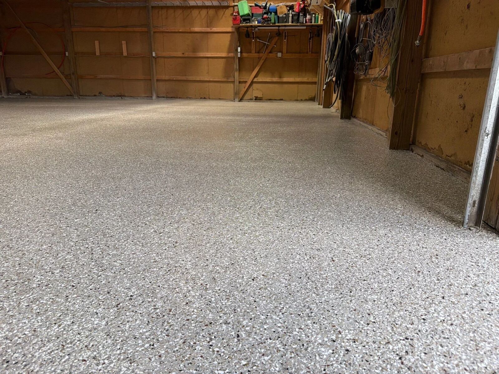 Finished coated shop floor in a workshop with tools and storage along the walls